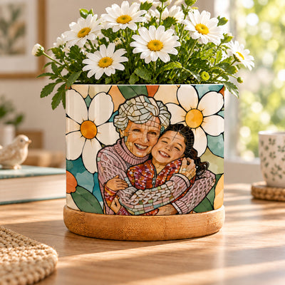 Personalized plant pot couple photo showing a grandmother hugging a girl, white daisies and bamboo tray on a wooden table