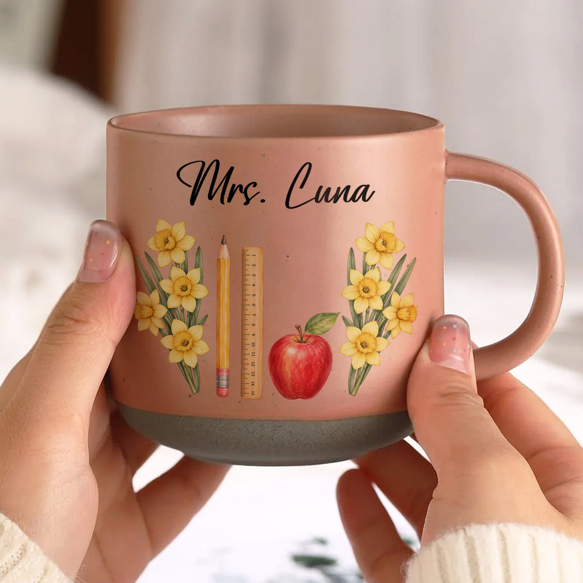 Personalized pottery mug custom teacher name pink mug with yellow daffodils held in two hands, pencil, ruler and apple