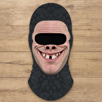 Funny Personalized Ski Mask laid flat on a wood surface, black paisley fabric with a printed grinning face
