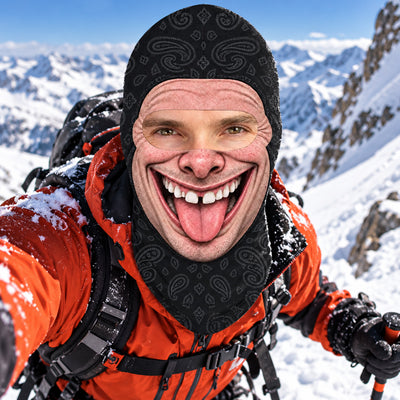 Funny Personalized Ski Mask worn by a climber in an orange jacket sticking out his tongue in the snow