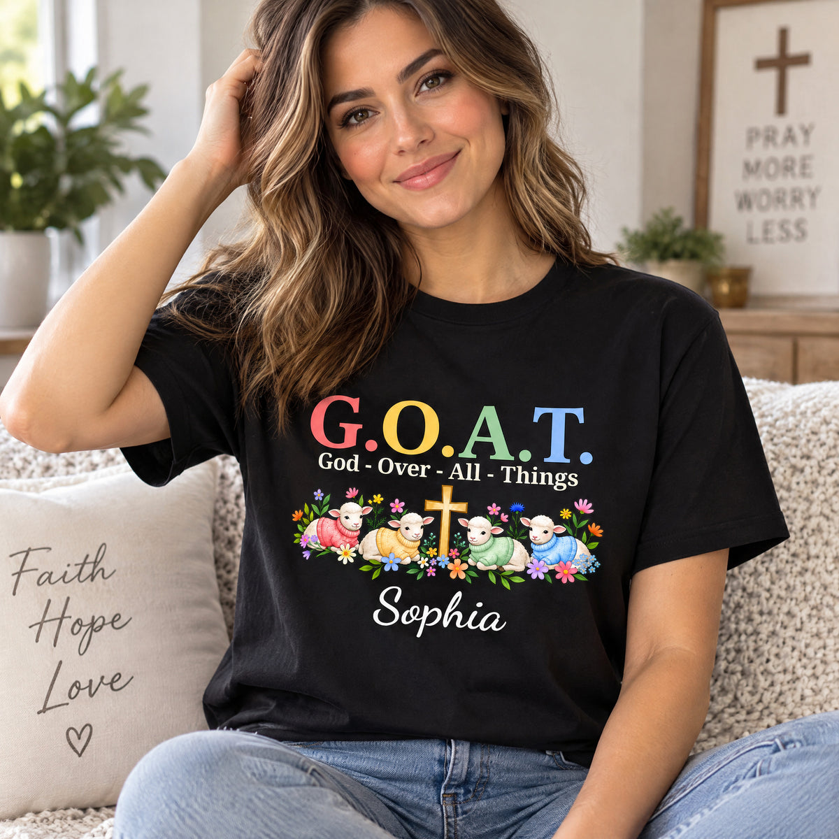 Personalized G.O.A.T. God Over All Things Shirt worn on a couch beside a Faith Hope Love pillow