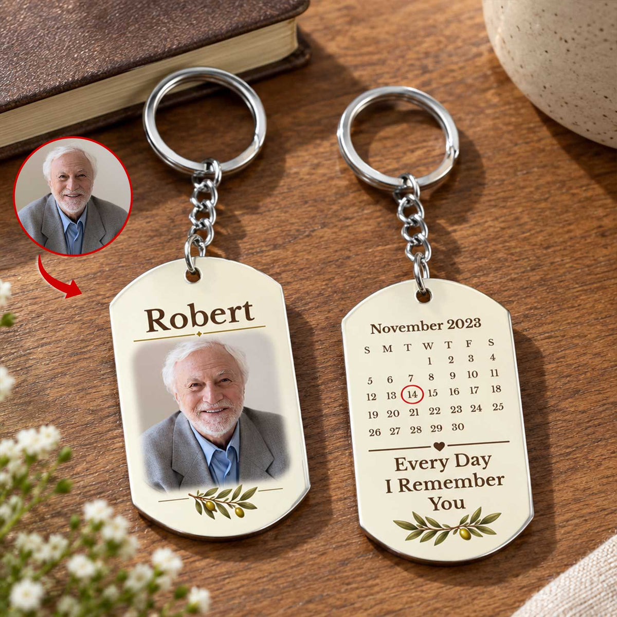 Personalized stainless steel memorial keychain front and back on a wooden table beside a book and a small photo inset