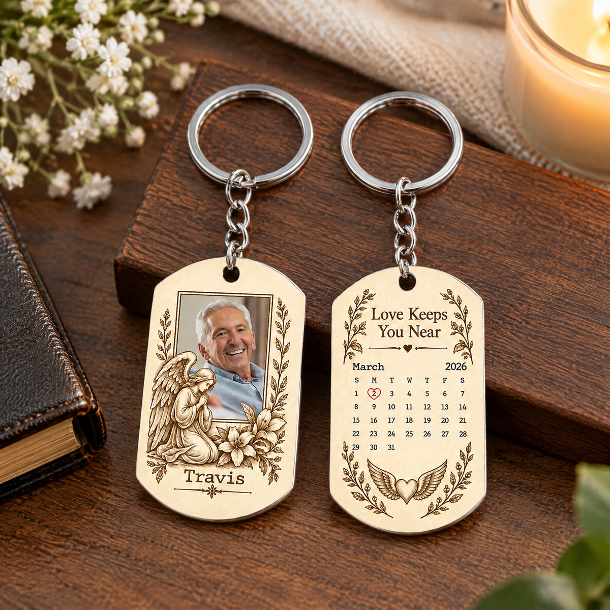 Personalized Stainless Steel Memorial Keychain on a dark box with white flowers, a candle and a book nearby