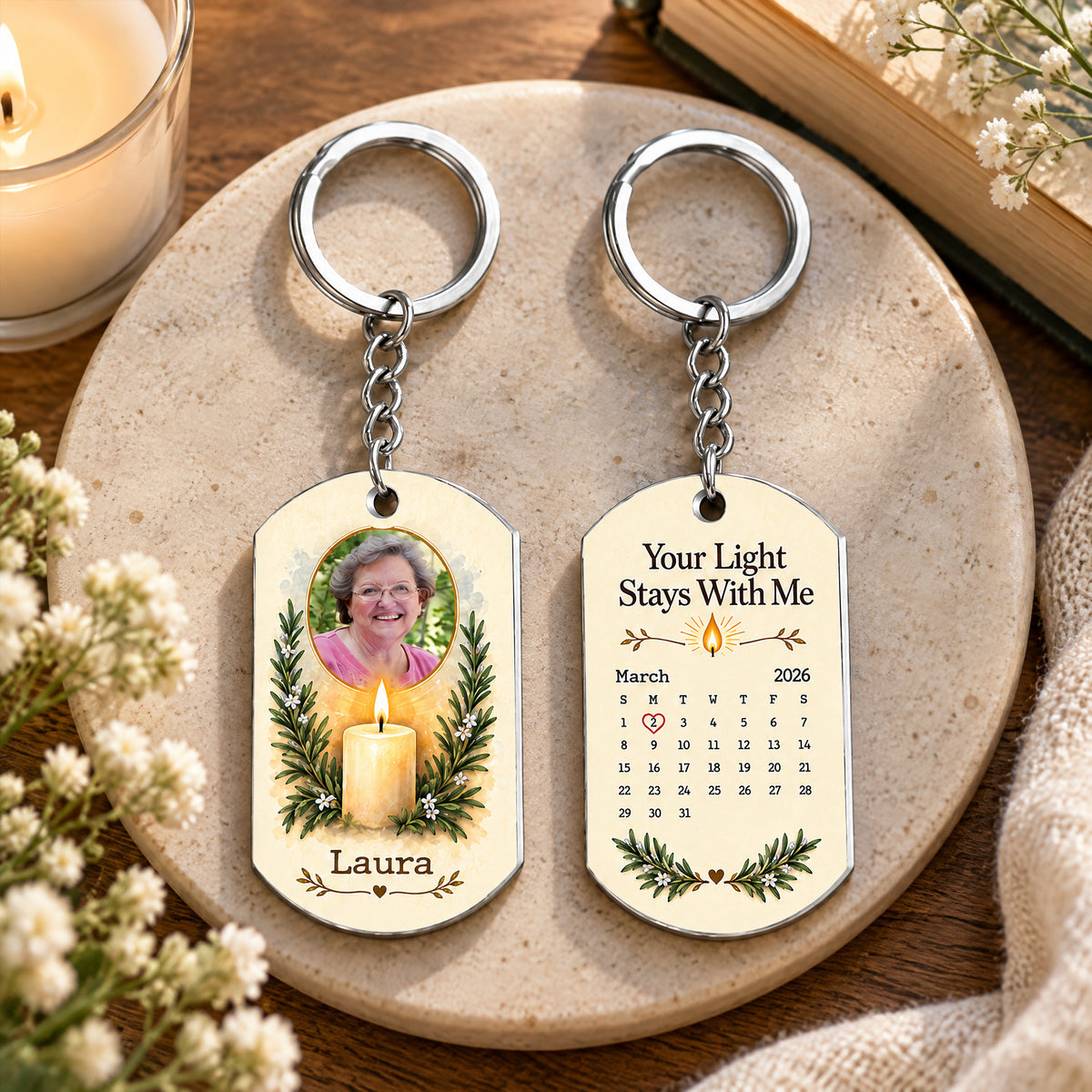 Personalized stainless steel memorial keychain front and back on a round stone tray with a candle and flowers