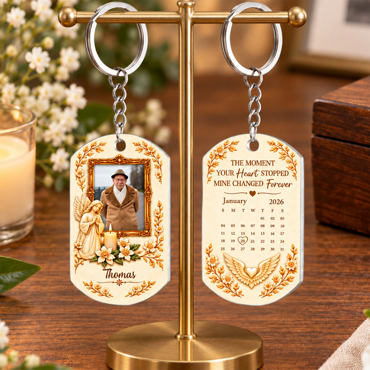 Personalized Stainless Steel Memorial Keychain pair hanging from a brass stand with flowers and a candle behind
