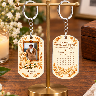 Personalized Stainless Steel Memorial Keychain pair hanging from a brass stand with flowers and a candle behind