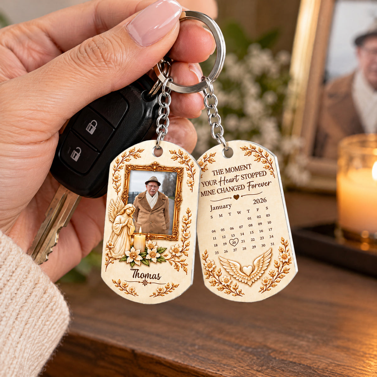 Personalized Stainless Steel Memorial Keychain held in a hand with car keys, a framed photo and candle behind