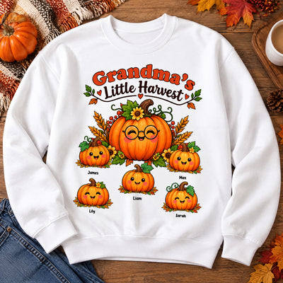 Grandma's Little Harvest Personalized Sweatshirt laid flat on a wooden table with jeans, pumpkins and autumn leaves