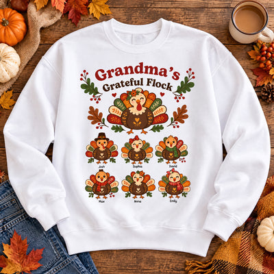 Grandma's Grateful Flock Personalized Sweatshirt flat lay in white with six named turkeys, leaves, pumpkins and jeans