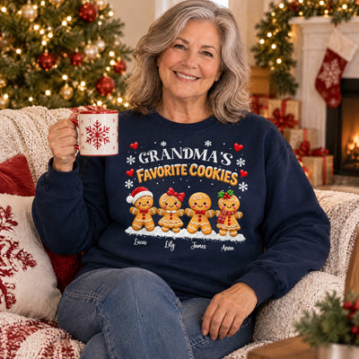 Personalized Grandma's Favorite Cookies Sweatshirt on a woman seated on a sofa with a mug, stocking and tree behind