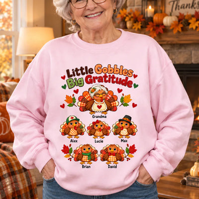 Personalized Little Gobbles Big Gratitude Sweatshirt in pink on a smiling woman by a fireplace, five turkeys with names