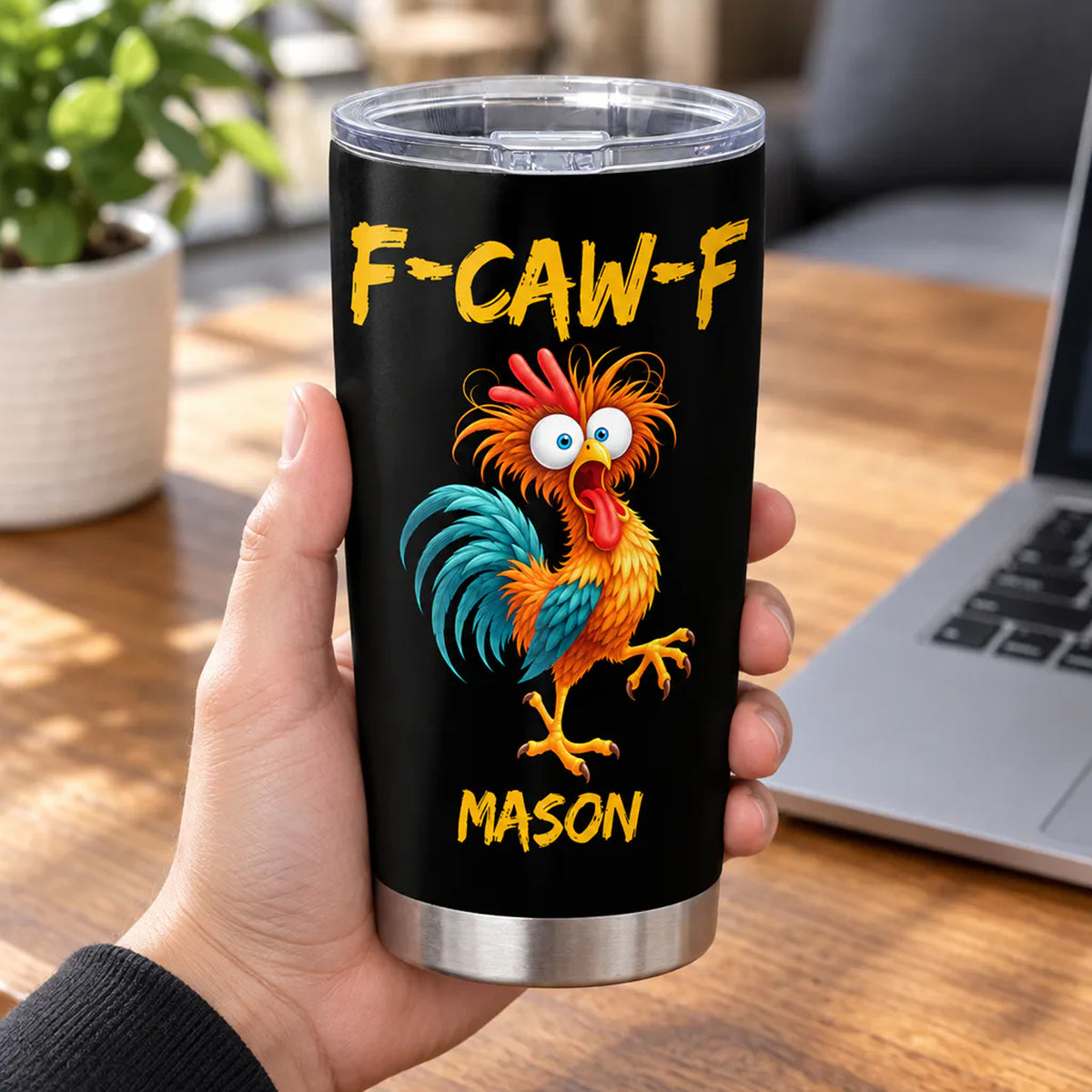 Personalized tumbler custom name rooster design held in a hand near a laptop and potted plant