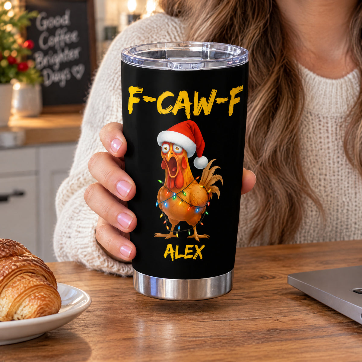 Personalized tumbler custom name rooster design held by a woman in a sweater beside a croissant on a table