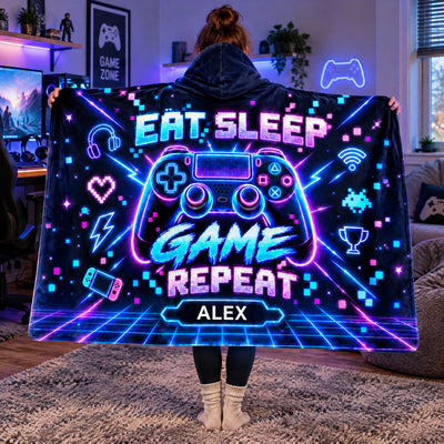 Personalized wearable hooded blanket held wide in a living room with a gaming monitor and bean bag