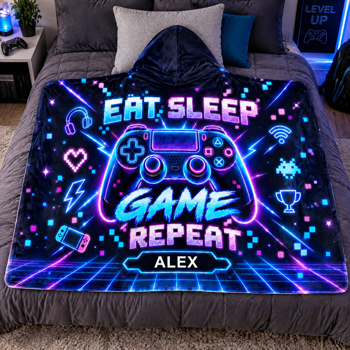 Personalized wearable hooded blanket laid flat on a gray bed with pillows and a game controller nearby