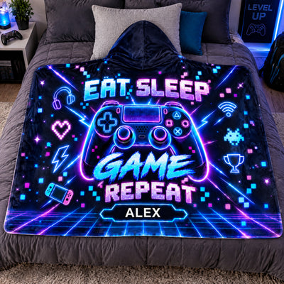 Personalized wearable hooded blanket laid flat on a gray bed with pillows and a game controller nearby