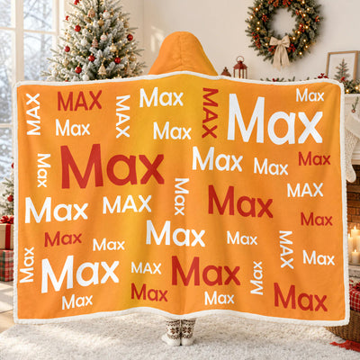 Personalized Wearable Hooded Blanket in orange with Max name pattern, worn from behind beside a Christmas tree