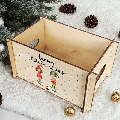 Personalized wooden treasure chest seen from above, open inside, on white fluffy fur with pine cones and gold baubles